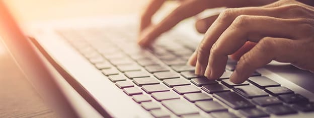 Nahaufnahme von Händen beim Tippen auf einer Laptop-Tastatur zur Veranschaulichung von Routineschritten zum PC-Schutz